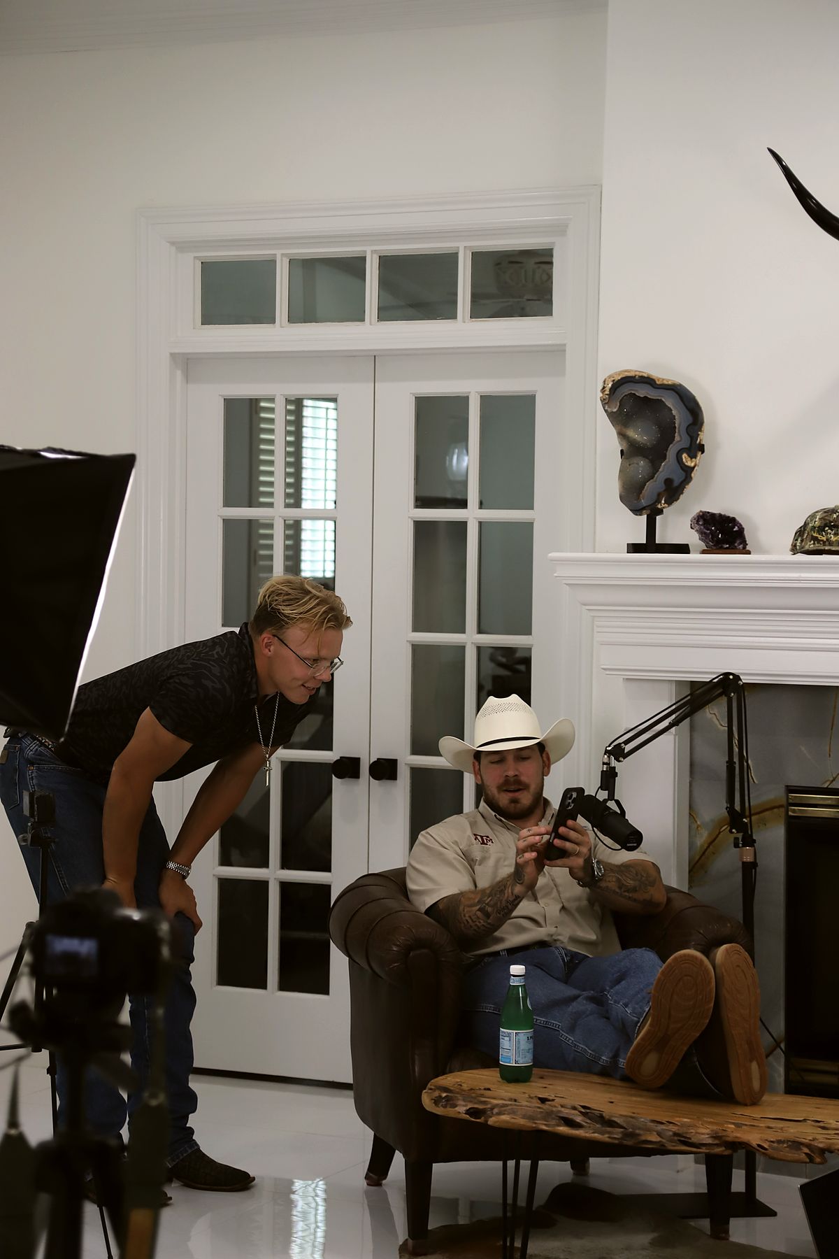A shooter leans in to review playback with the subject on a lit interview set